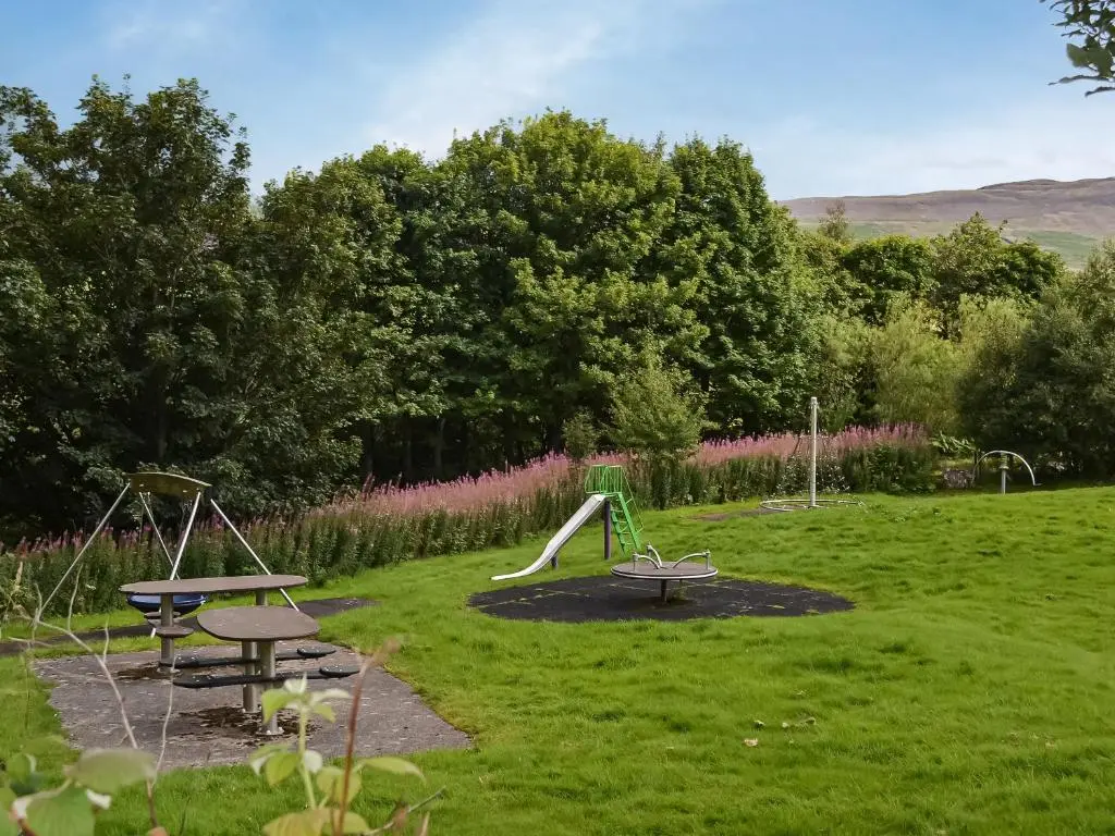 a park with two swings and a slide at Douneside Cottage in Inverness