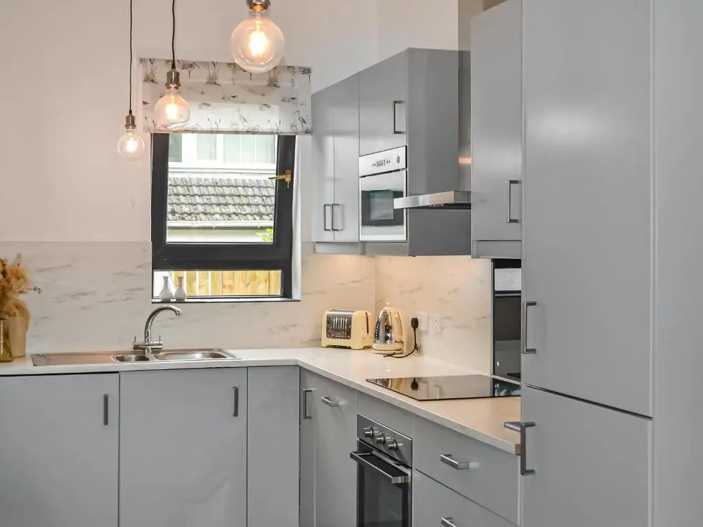 a white kitchen with a sink and a refrigerator at Douneside Cottage in Inverness