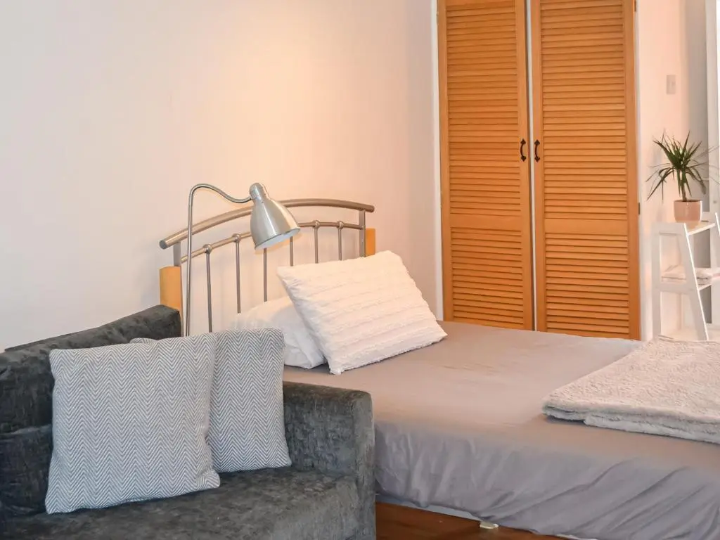 a bedroom with a bed and a couch and a lamp at Douneside Cottage in Inverness