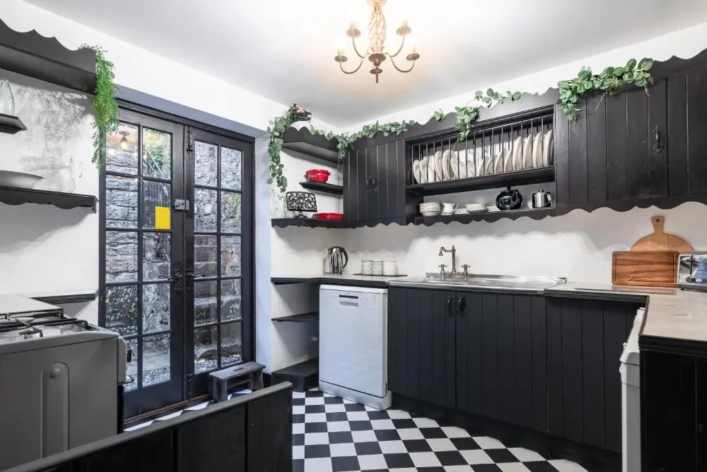 a kitchen with black cabinets and a checkered floor at Criss Cross Cottage in Inverness