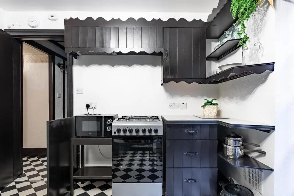 a kitchen with black cabinets and a stove at Criss Cross Cottage in Inverness