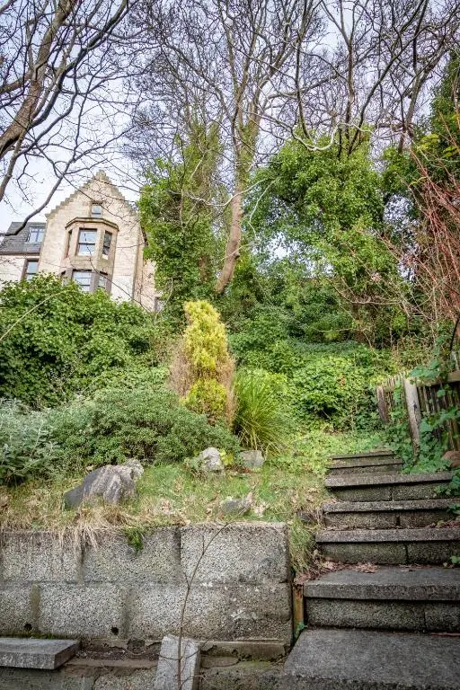 a house sitting on top of a hill with stairs at Criss Cross Cottage in Inverness