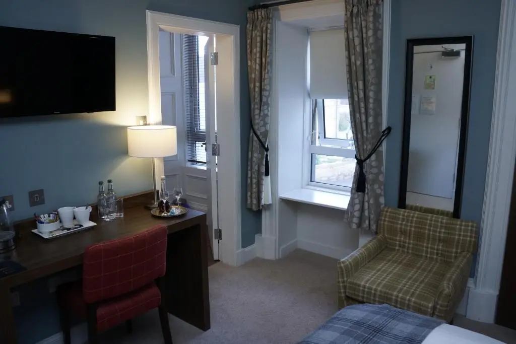a hotel room with a bed and a desk and a chair at Corriegarth Hotel in Inverness