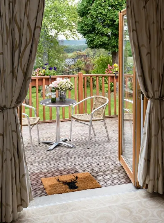 a patio with a table and chairs on a deck at Boat Country Inn and Restaurant in Boat of Garten