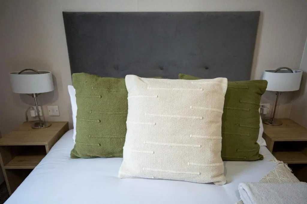 a bedroom with a bed with green pillows at Grantown Get Away - SJA Stays - Modern 2 Bed Static in Grantown on Spey