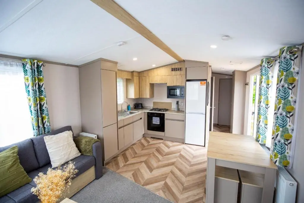 a living room with a couch and a kitchen at Grantown Get Away - SJA Stays - Modern 2 Bed Static in Grantown on Spey