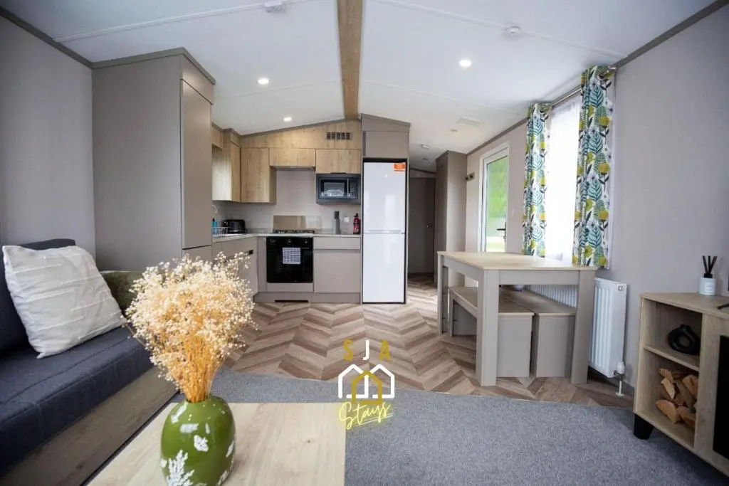 a living room with a blue couch and a kitchen at Grantown Get Away - SJA Stays - Modern 2 Bed Static in Grantown on Spey