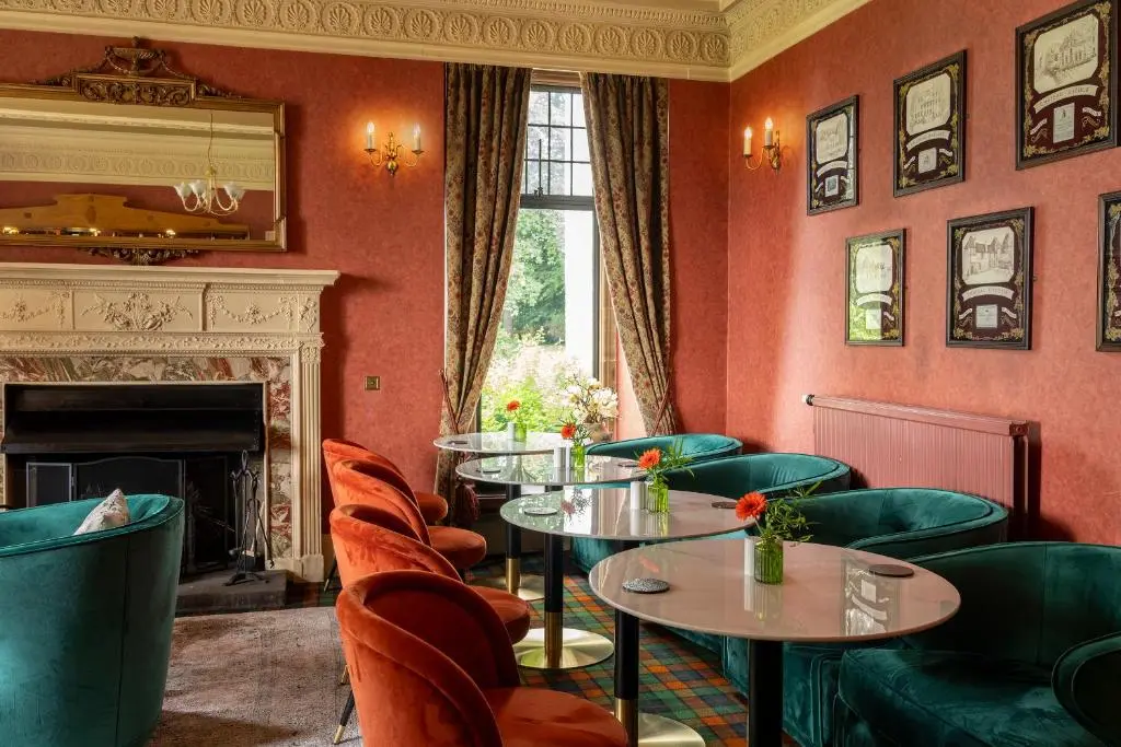 a restaurant with tables and chairs and a fireplace at Kincraig Castle Hotel in Invergordon