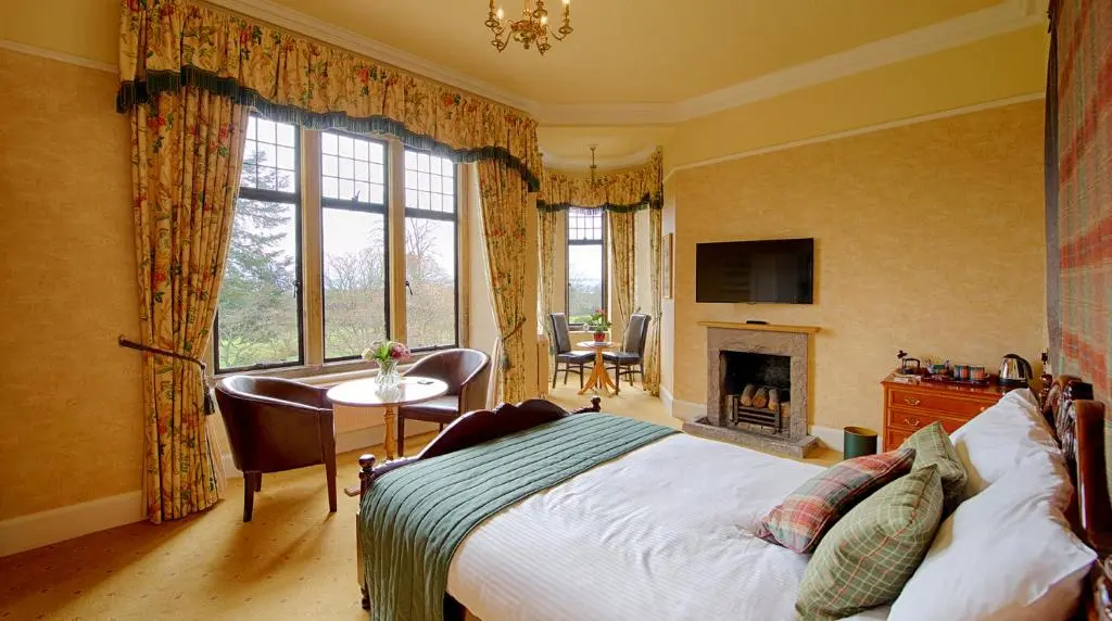 a bedroom with a bed and a desk and a fireplace at Kincraig Castle Hotel in Invergordon