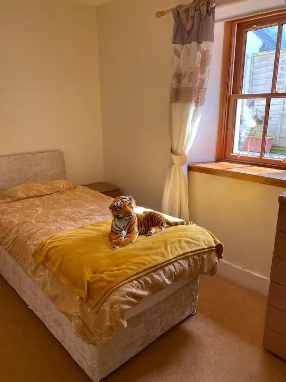 a stuffed tiger sitting on a bed in a bedroom at 2 Bed Cottage Sleeps 4-Pets Welcome-Private Garden in Buckie