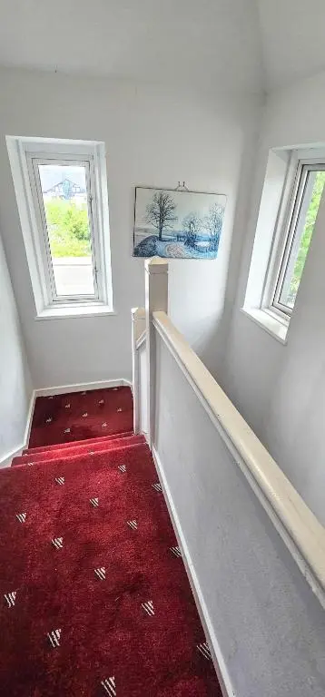 a staircase with a red carpet and two windows at 1 Bedroom House - Inverness - River Canal in Inverness