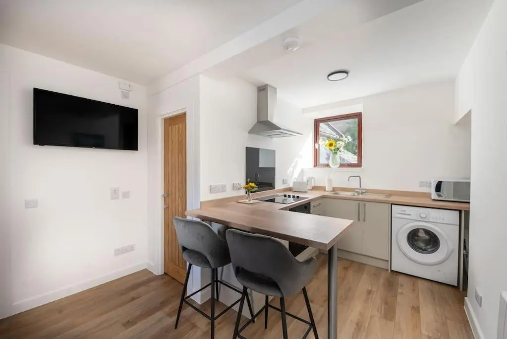 a kitchen with a sink and a counter with stools at Town centre flat in Inverness