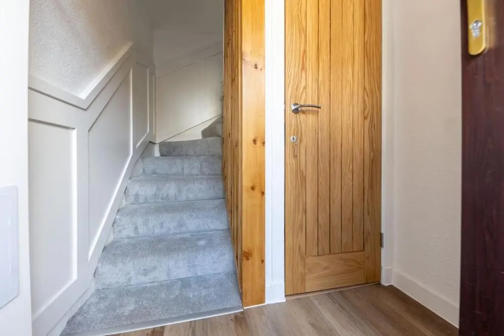 a hallway with stairs with a wooden door at Town centre flat in Inverness