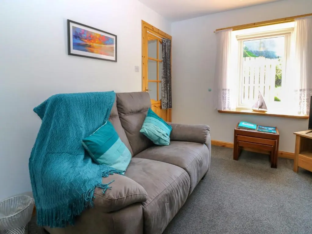 a living room with a brown couch with blue pillows at Jade Cottage in Macduff