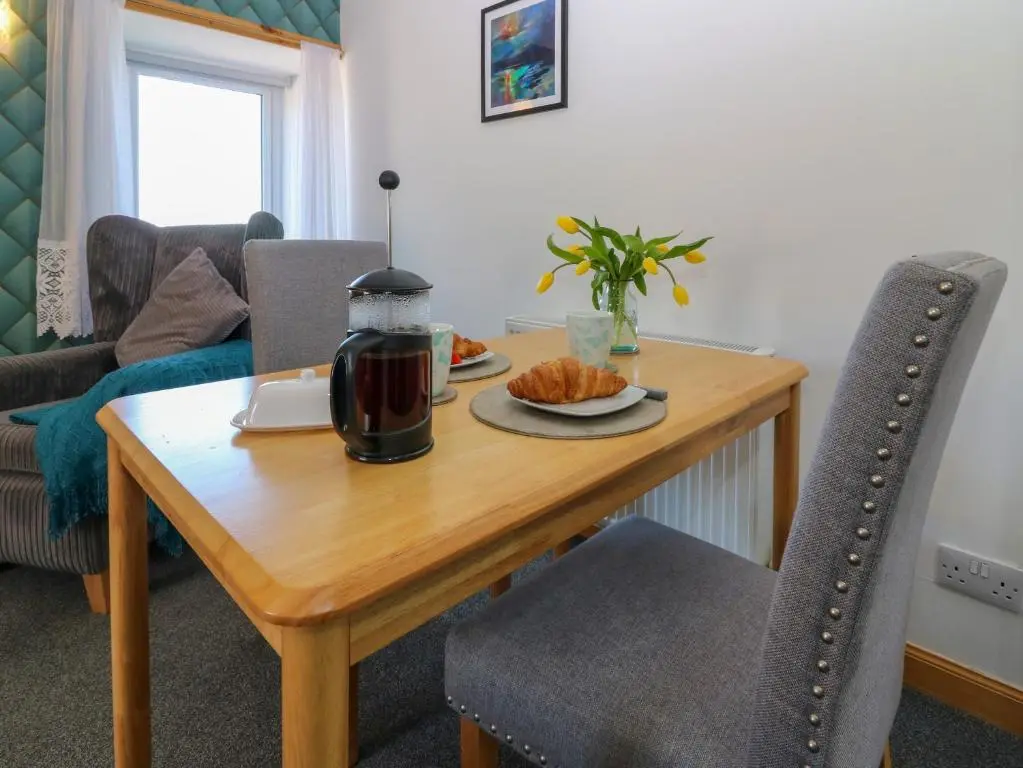 a wooden table with a plate of food on it at Jade Cottage in Macduff
