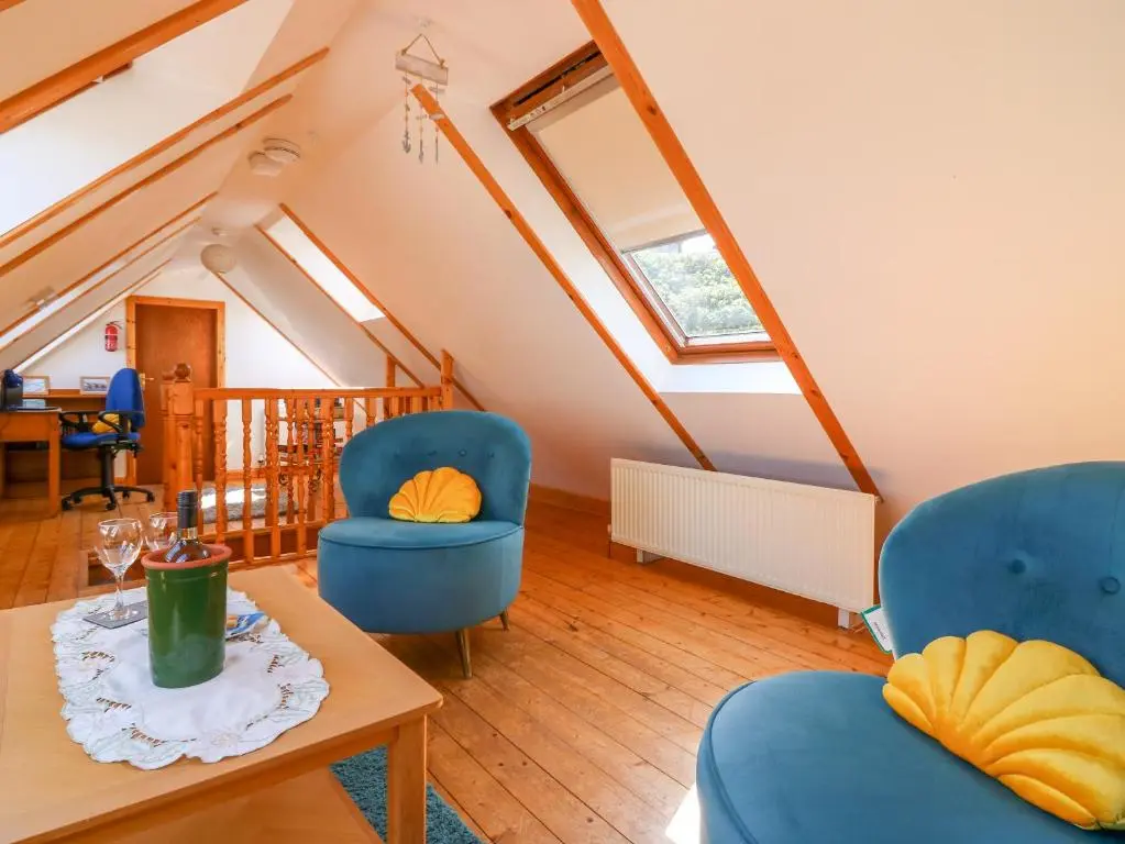 a living room with two blue chairs and a table at Jade Cottage in Macduff