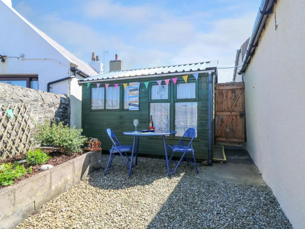 a tiny house with a table and chairs in a yard at Jade Cottage in Macduff