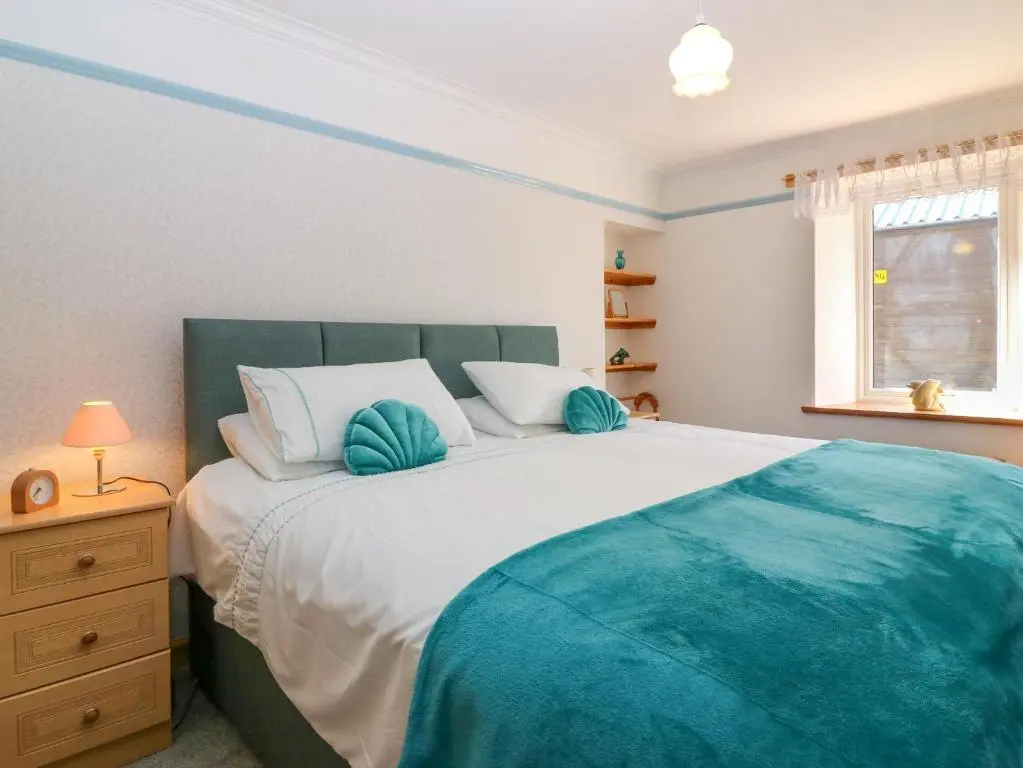 a bedroom with a large bed and a window at Jade Cottage in Macduff