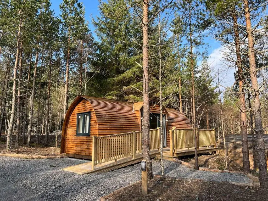 a log cabin in the woods with a tree at Glenlivet by Wigwam Holidays in Tomintoul