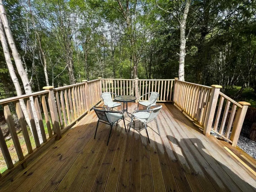 a wooden deck with two chairs and a table on it at Glenlivet by Wigwam Holidays in Tomintoul