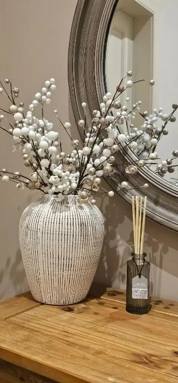 a white vase with flowers in it on a table at Balmore Farmhouse near Lochness in Inverness
