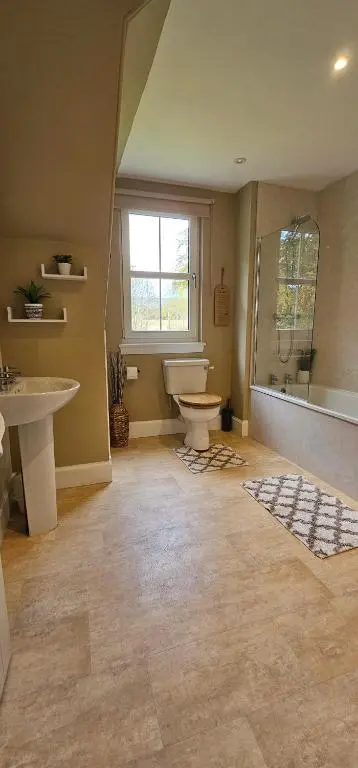a bathroom with a toilet and a sink and a window at Balmore Farmhouse near Lochness in Inverness