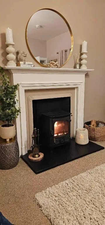 a living room with a fireplace with a mirror at Balmore Farmhouse near Lochness in Inverness