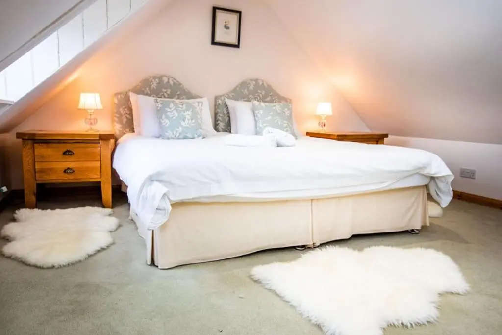 a bedroom with a large bed with white sheets and pillows at Grieves Cottage, near Dornoch in Dornoch