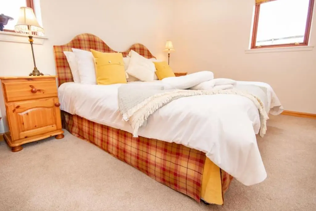a bedroom with a large bed with yellow and white pillows at Grieves Cottage, near Dornoch in Dornoch