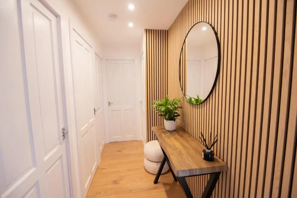 a hallway with a wooden table and a mirror at Two Bedroom Hilton Apartment 1st floor in Inverness
