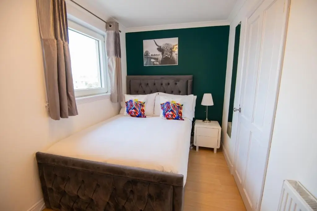 a bedroom with a large bed with a window at Two Bedroom Hilton Apartment 1st floor in Inverness