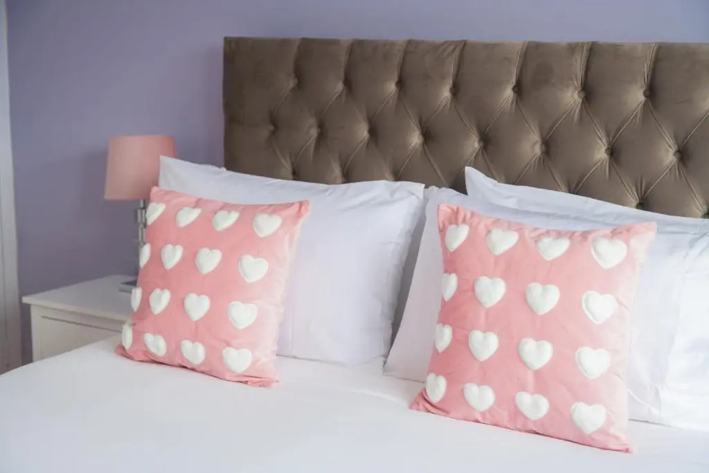 a bed with pink pillows and white pillows at Two Bedroom Hilton Apartment 1st floor in Inverness