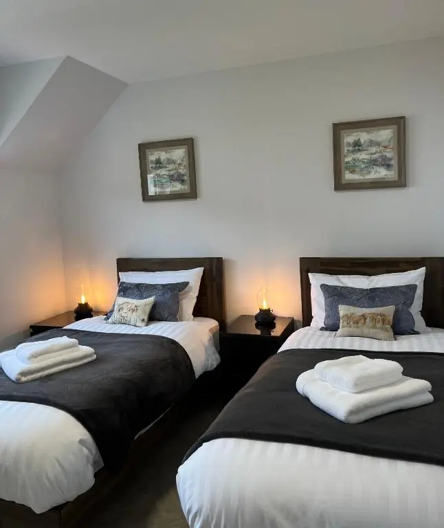 a bedroom with two beds with towels on them at The Beech House in Aviemore