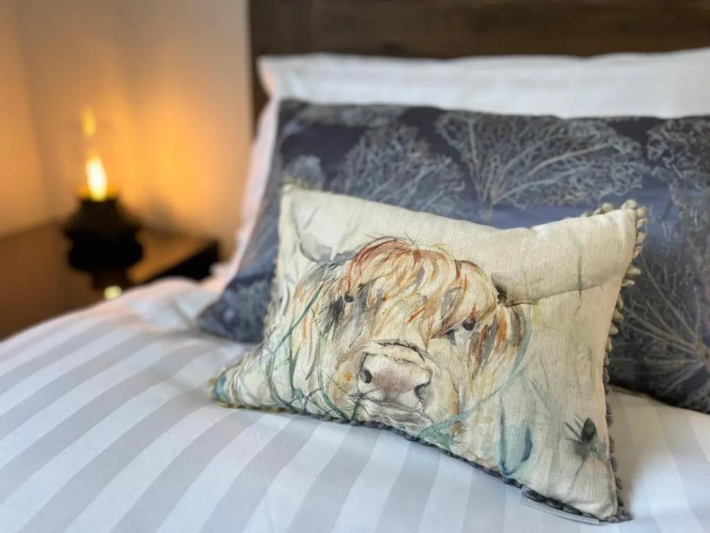 a painting of a dog on a pillow on a bed at The Beech House in Aviemore