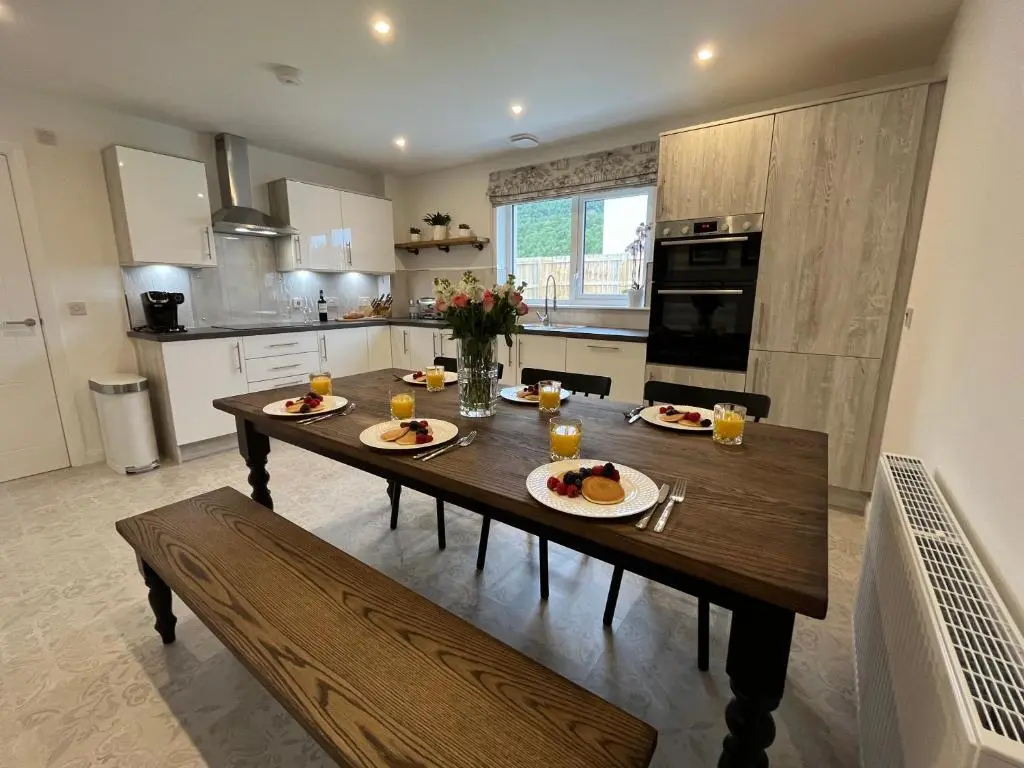 a kitchen with a wooden table with plates of food on it at The Beech House in Aviemore