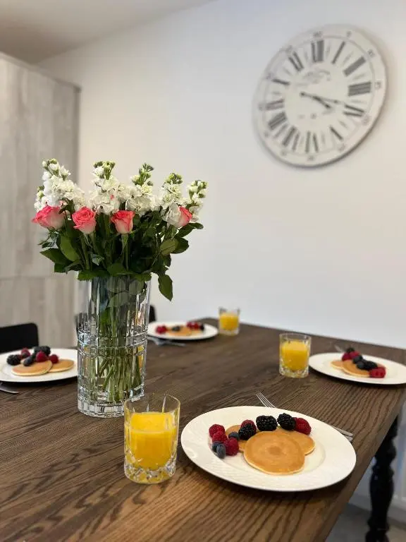 a table with plates of food and a vase with flowers at The Beech House in Aviemore