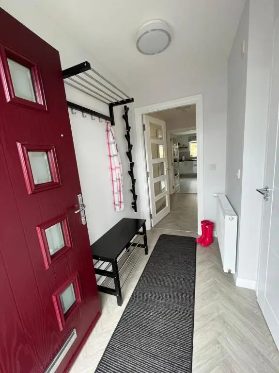 a red door in a hallway with a black rug at The Beech House in Aviemore