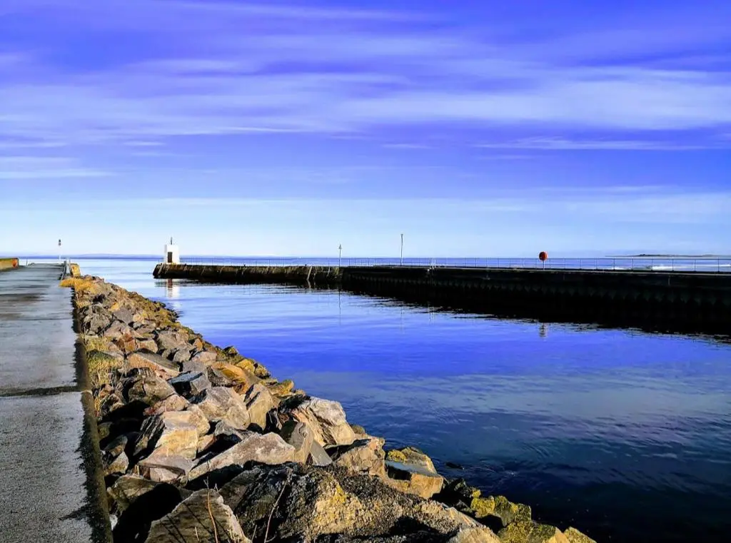 a large body of water with a pier and a lighthouse at The Lighthouse in Nairn