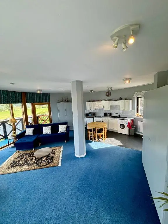a living room with a blue carpet and a kitchen at The Lighthouse in Nairn