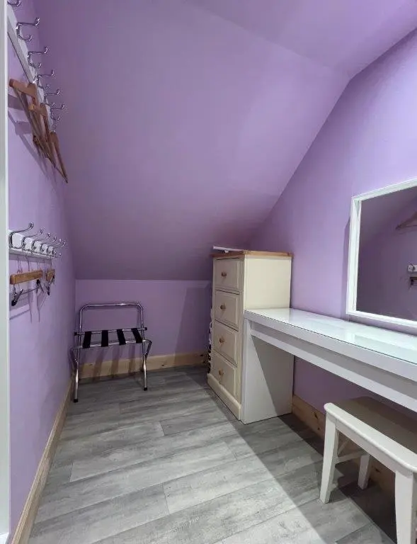 a purple attic room with a bed and a dresser at Endeavour Guest House in Aberdeen