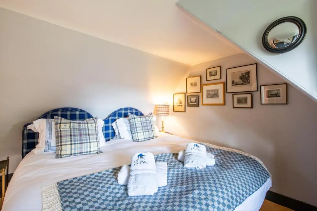 a bedroom with a bed with blue and white pillows at Dun Brae Cottage in Dornoch