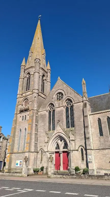 an old church with a tower and red doors at The Wee Heilan' Coo in Nairn