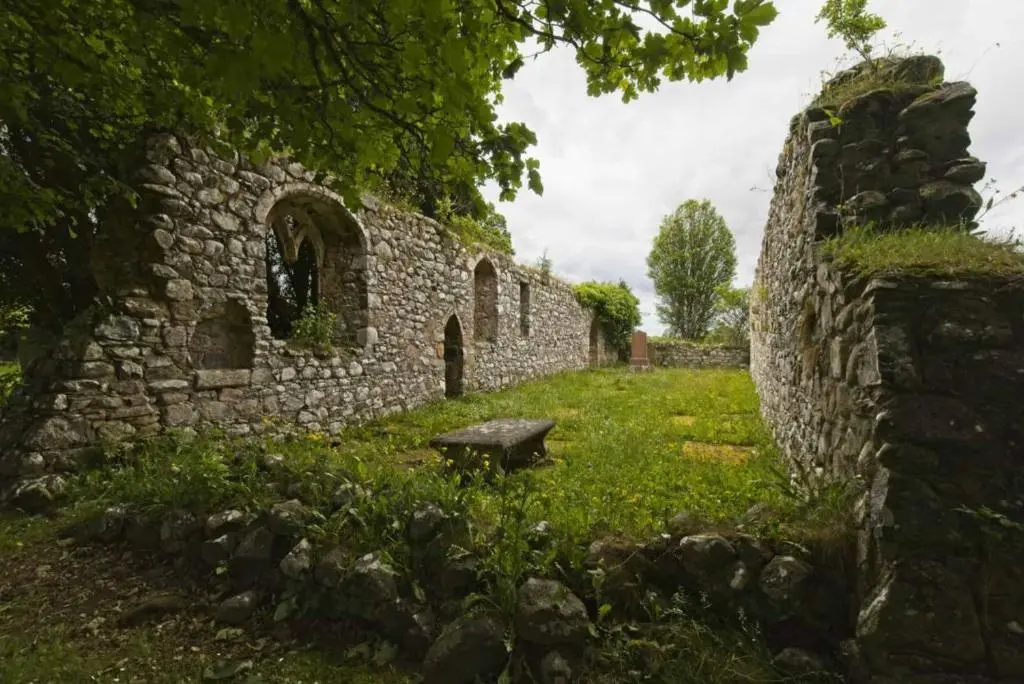 an old stone building with a bench in the grass at The Wee Heilan' Coo in Nairn