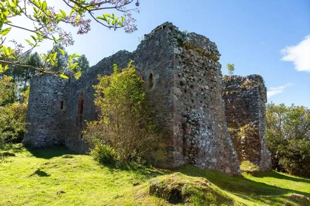 an old stone building on a grass field at The Wee Heilan' Coo in Nairn