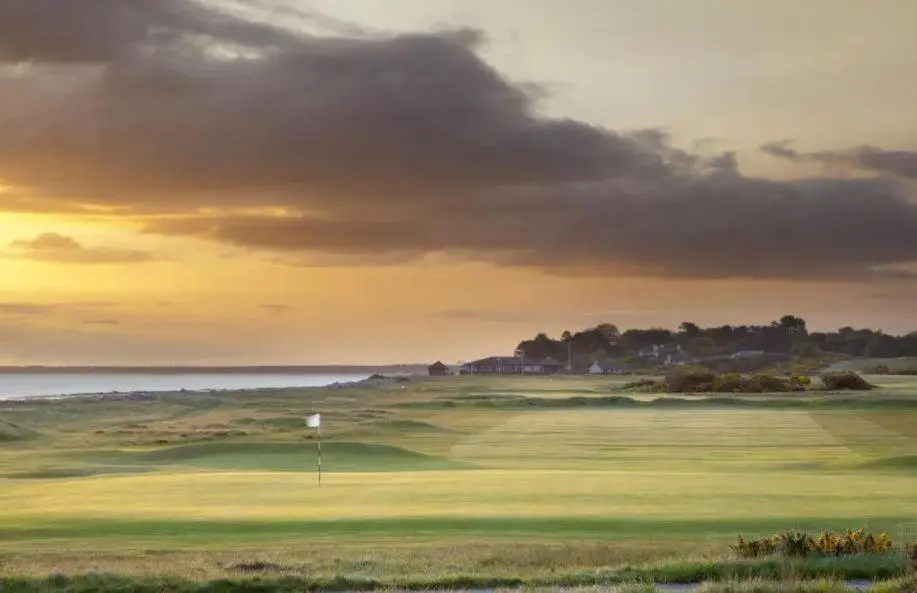 a view of a golf course with the ocean in the background at The Wee Heilan' Coo in Nairn