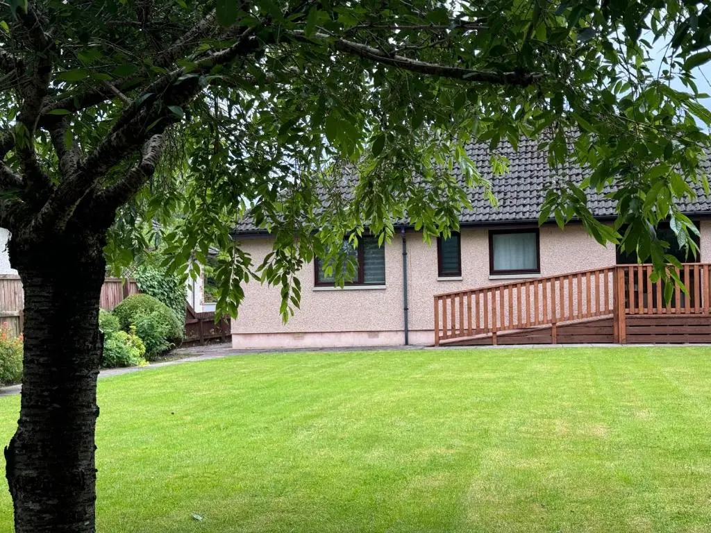 a house with a tree in front of a yard at Oaklyn,Highland Village of Beauly, Quiet Neighbourhood, One Bed, Min 5 nights in Beauly