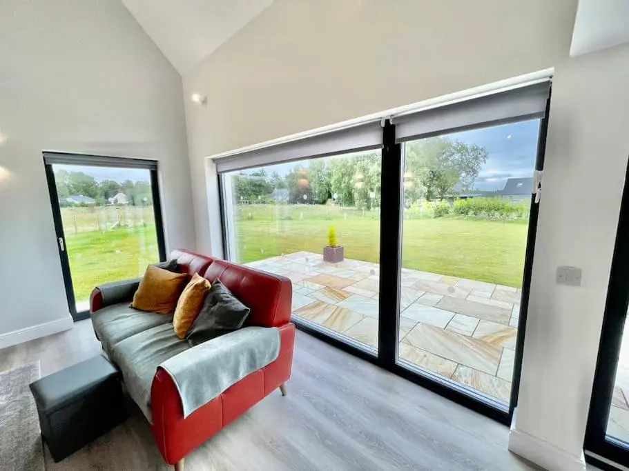 a living room with a red couch and a large window at Ash Mill - Dornoch in Dornoch