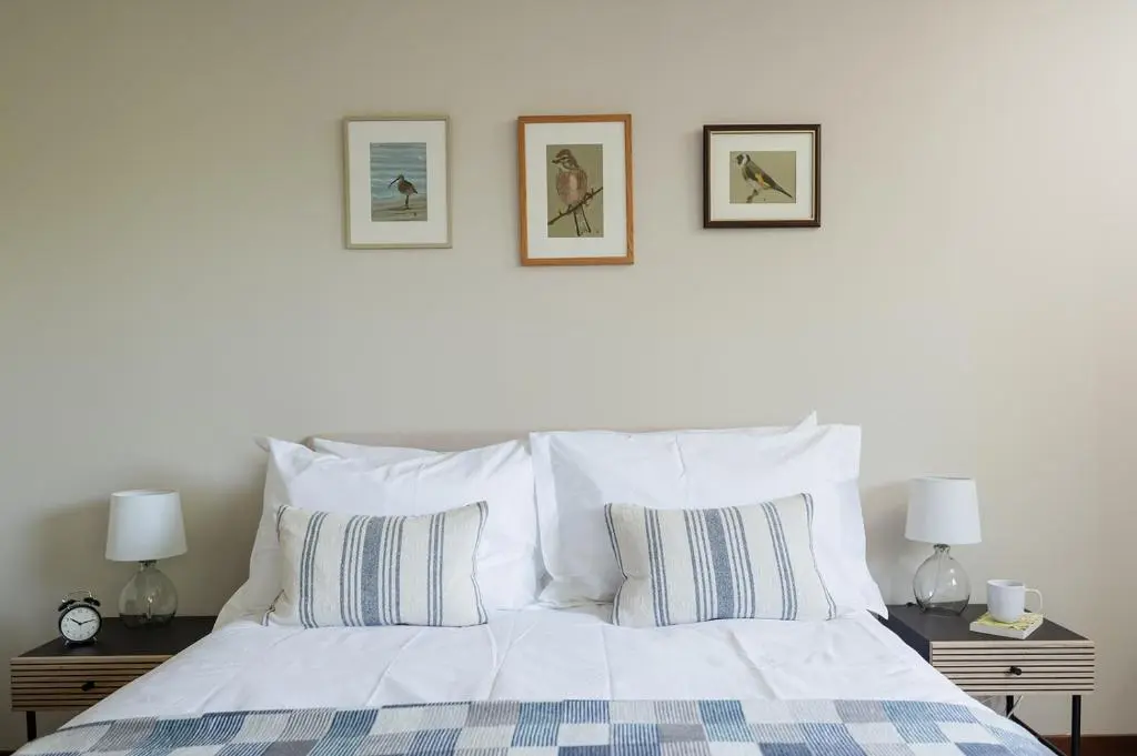 a bedroom with a white bed with three pictures on the wall at Fairways - Seasgair Lodges in Nairn