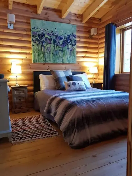 a bedroom with a bed in a wooden cabin at Orchid lodge in Bridge of Tilt