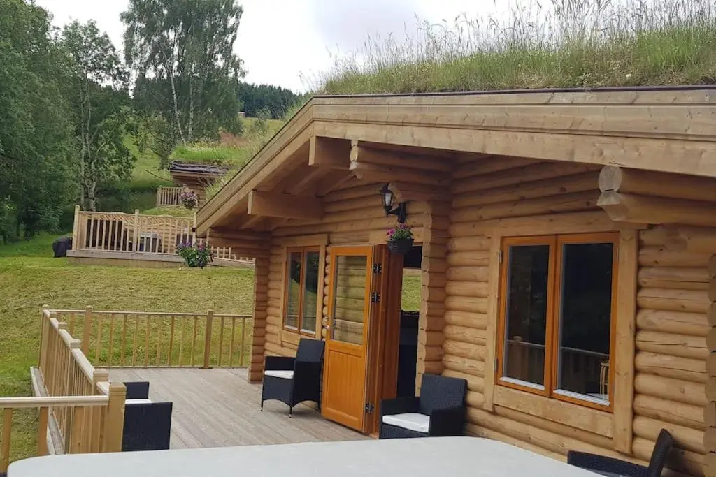 a log cabin with a porch with a grass roof at Orchid lodge in Bridge of Tilt